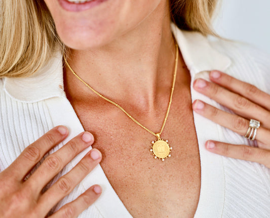 Woman wearing a gold necklace and smiling.
